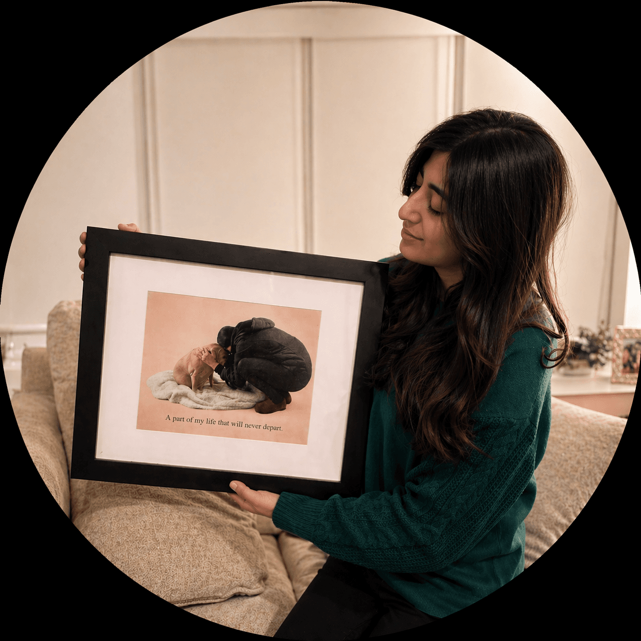 Woman in a green sweater holding a framed photo of a person hugging a dog.